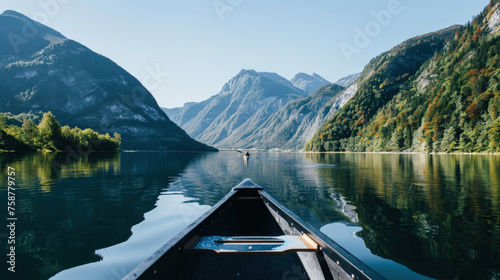 A boat is seen floating in the center of a lake, surrounded by towering mountains in the background © sommersby