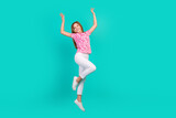Full size photo of pretty teenager girl jumping raise hands wear trendy print pink outfit isolated on cyan color background