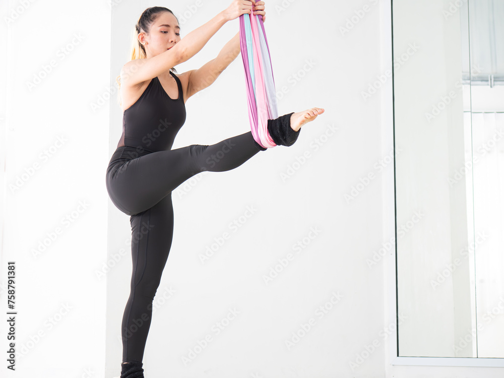 Young beautiful Asian dancer dressed in black color warming up and stretching before aerial dance at the studio.