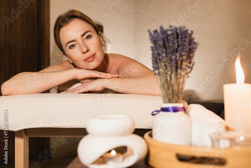Body massage. Serene massage space adorned with candles and lavender for massage treatment of beautiful woman lying on massage table