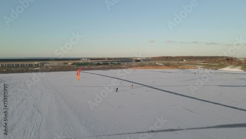 Cornwerd, Netherlands - 15 February 2022: Aerial view of people snowkiting sport on frozen ice lake in winter, Netherlands