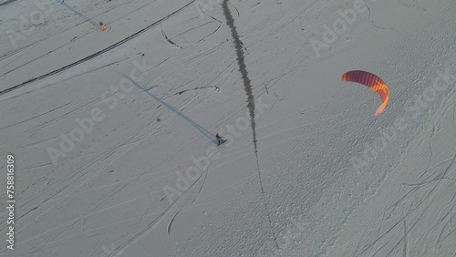 Aerial view of people snowkiting sport on frozen ice lake in winter, Netherlands