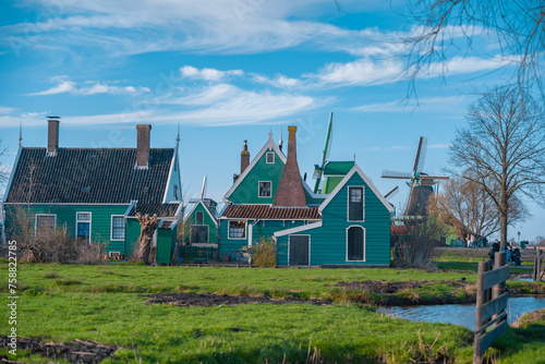 Traditional Dutch windmills in the rural landscape of Zaanse Schans village. Ancient houses brightly colored in spring season at sunset