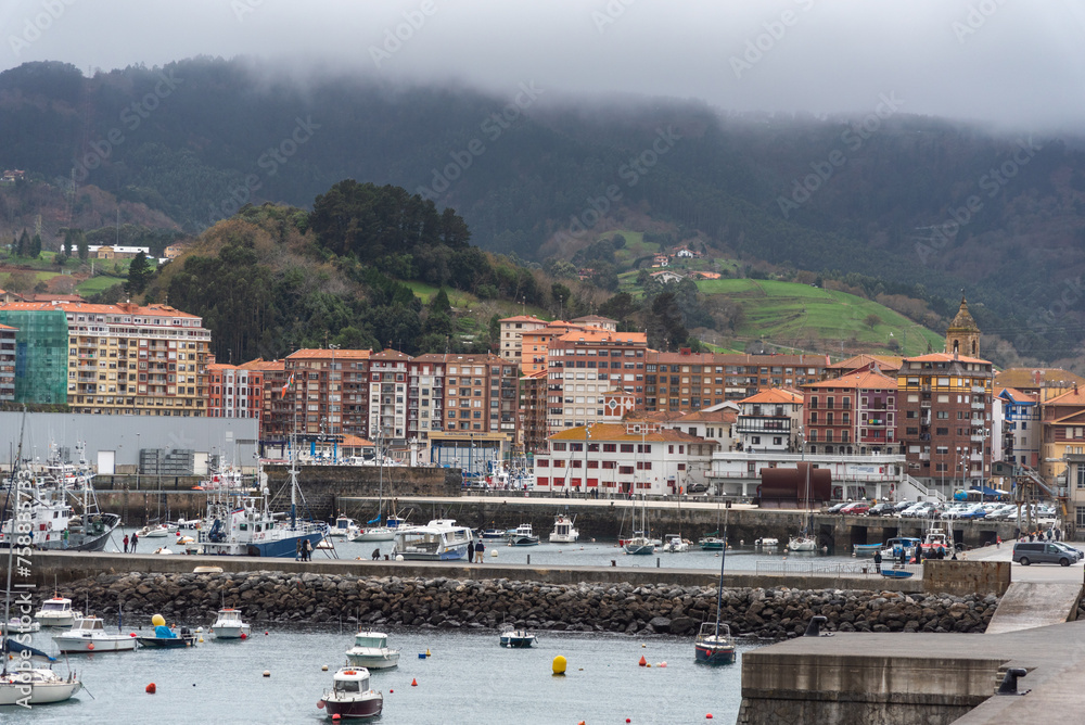 Panoramic view of the touristic small town on the coast of Biscay Bermeo with a small harbour full of boats and small houses with colourful facades.