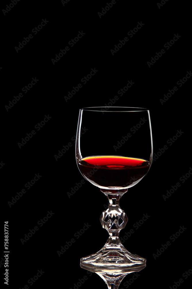 Red grape wine in a glass. On a black background. Glass crystal goblets. Pouring from a bottle. Place for text. Red grape wine in a glass. On a black background. Glass crystal goblets. Pouring from a bottle. Place for text.