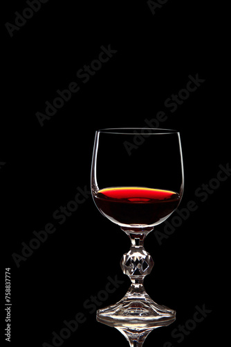 Red grape wine in a glass. On a black background. Glass crystal goblets. Pouring from a bottle. Place for text.
