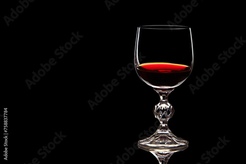 Red grape wine in a glass. On a black background. Glass crystal goblets. Pouring from a bottle. Place for text.	