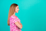 Photo of pretty teenager girl crossed hands profile look empty space wear trendy print pink outfit isolated on cyan color background