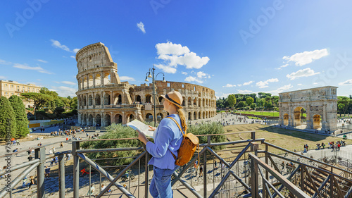  Happy woman tourist looking up from map at Rome Colosseum