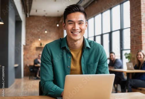 A joyful man using a laptop in a vibrant office environment.