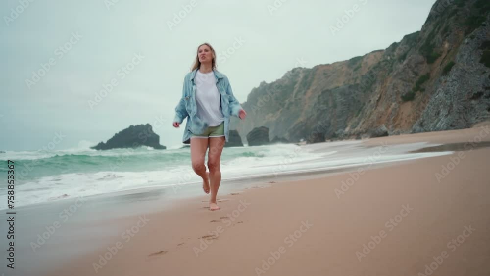 Happy woman running ocean beach, smiling at camera. Happy female traveler dressed denim shirt walk sandy sea beach, holiday vacation Happy woman running ocean beach, smiling at camera. Happy female traveler dressed denim shirt walk sandy sea beach, holiday vacation