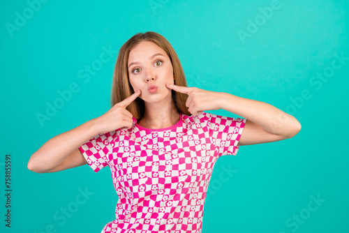 Photo portrait of pretty teenager girl fingers point cheeks plump lips wear trendy print pink clothes isolated on cyan color background