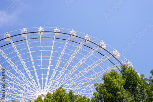 Part of ferris wheel in white color against summer blue sky © branislav