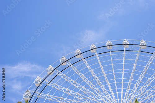Part of ferris wheel in white color against summer blue sky
