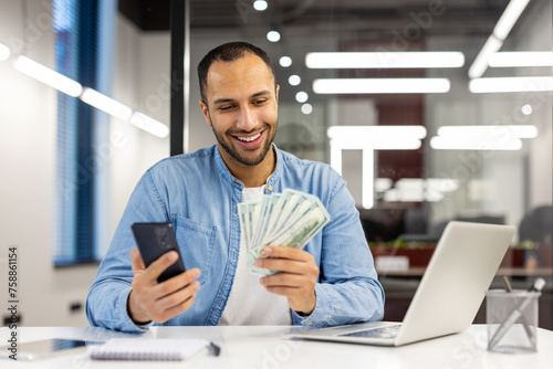Smiling man with money and smartphone in office