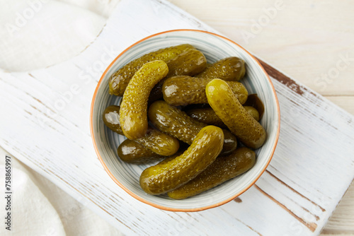 Marinated cucumbers in bowl on a light wooden background. Homemade pickles. 