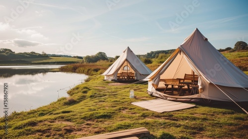 Lakeside glamping tents with wooden picnic tables.