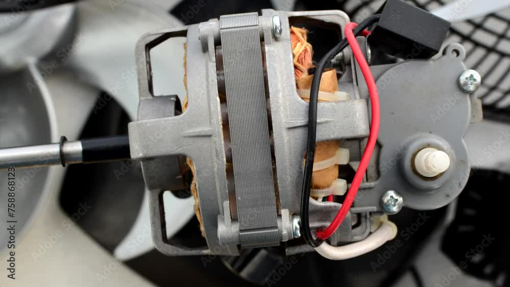 Close-up of an open fan motor, showcasing intricate wires and copper components in an industrial composition. Close-up of an open fan motor, showcasing intricate wires and copper components in an industrial composition.