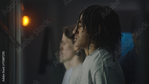 Foto African American teenager stands near prison cell with Caucasian boys, looks at the camera
