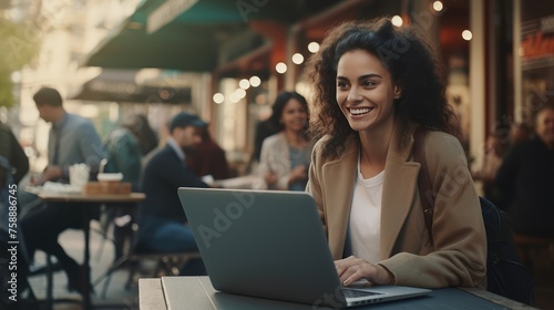 Smiling Young Woman Working on Laptop at Outdoor Cafe During Golden Hour