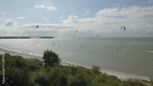 Aerial view of people doing kite surfing along the beach sunny day, Netherlands