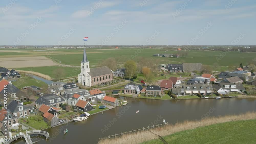 Aerial view of dutch flag on top of church (Johanneskerk) at sunny day during kingsday (Koningsdag), Oosthem, Friesland, Netherlands