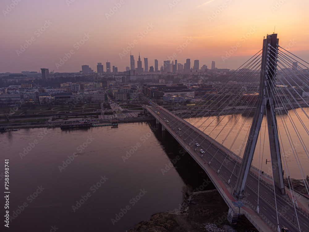 Bridge leading to a skyline of Warsaw at sunset, aerial