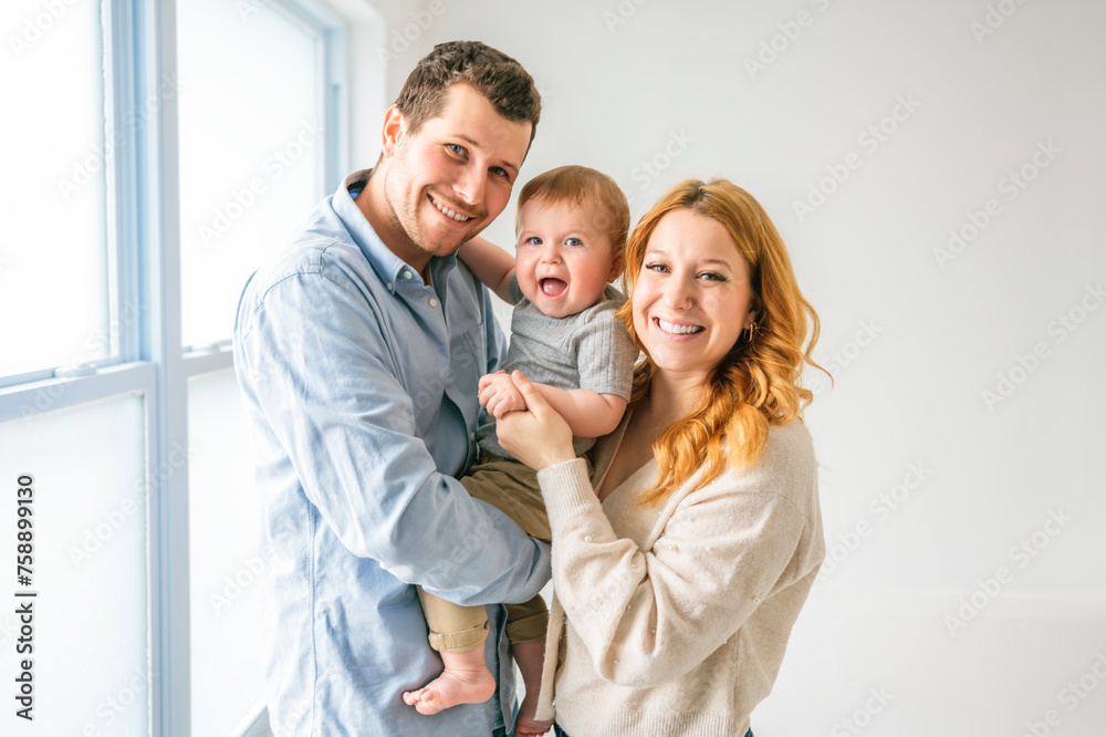 young beautiful family couple with baby boy on gray studio