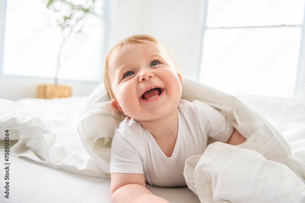 Baby boy in white sunny bedroom. one years child relaxing in bed. - obrazy, fototapety, plakaty 