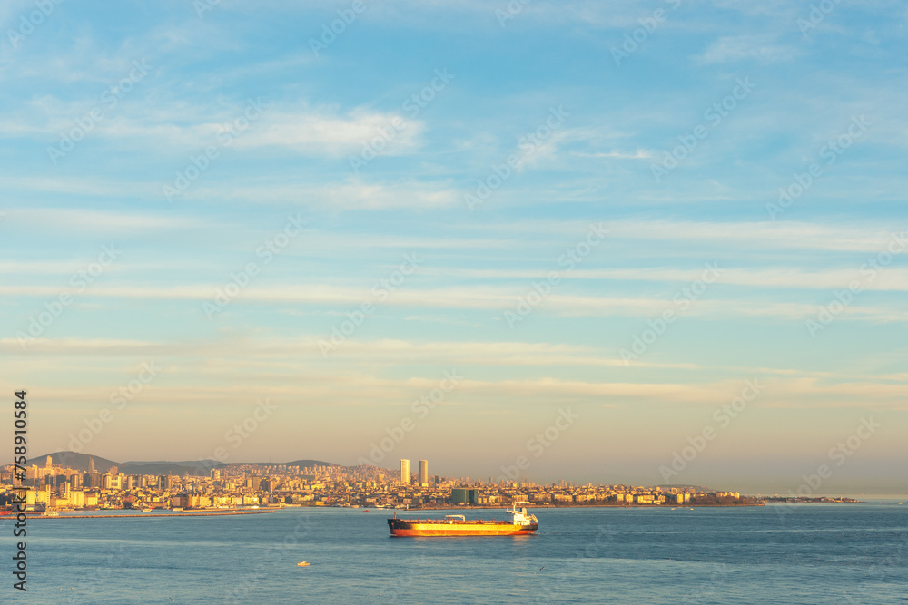 Cargo ship moving through Bosphorus during sunset.