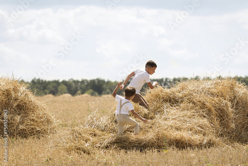 Children run through a haystack in a field in summer