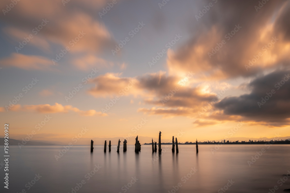 Ruins of wooden pier in the beach sea and sky with sunset light