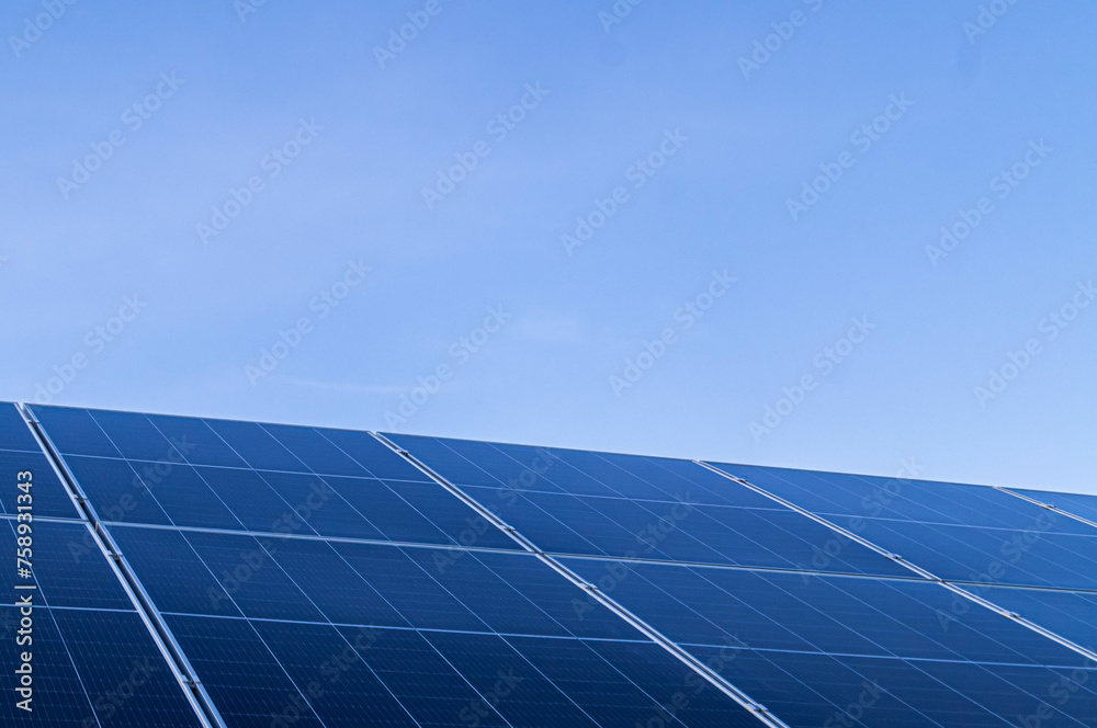 Clean energy production is captured here as photovoltaic panels reach skyward, intersecting technology with sustainability. A vast array of solar panels tilts towards the blue sky, harnessing the sun. Clean energy production is captured here as photovoltaic panels reach skyward, intersecting technology with sustainability. A vast array of solar panels tilts towards the blue sky, harnessing the sun.