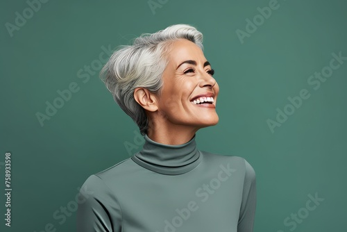 smiling mature woman with grey hair and closed eyes looking away isolated on green © Loli