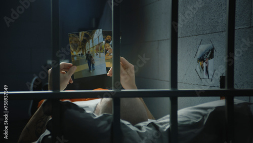 Εκτύπωση καμβά Male prisoner lies on bed in prison cell, looks at pictures of family