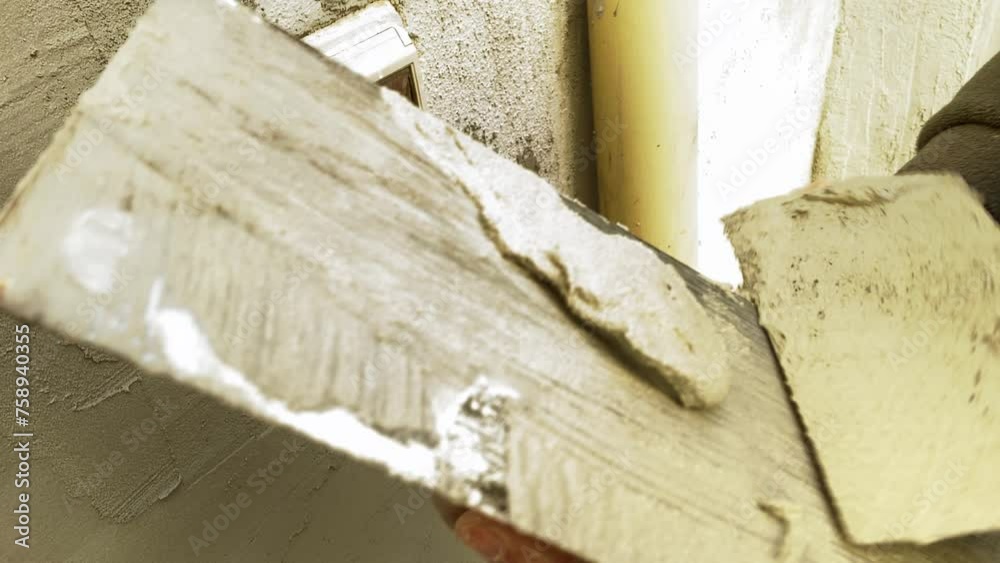 worker cleaning a trowel from the concrete with a spatula during construction work worker cleaning a trowel from the concrete with a spatula during construction work