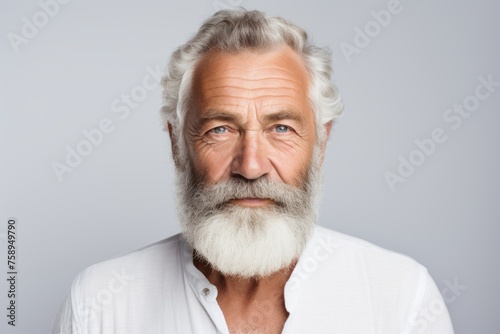 Portrait of a senior man with grey beard and mustache on grey background