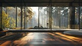 An empty room with wooden floors and large panoramic windows overlooking the forest emphasizes the minimalist aesthetic. Elegant room design with a forest view in the background.