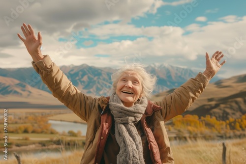 Waist up shot of happy good-looking elderly woman with hands in the air, beautiful landscape in the background