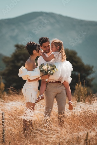 Capturing the beauty of love and family with stunning outdoor photograph featuring a young married couple embracing their adorable daughter.