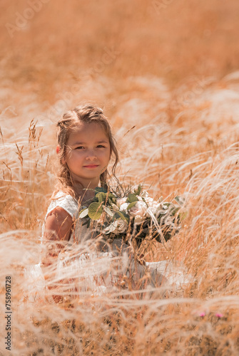 Little flower girl in white sitting in a field. wedding concept