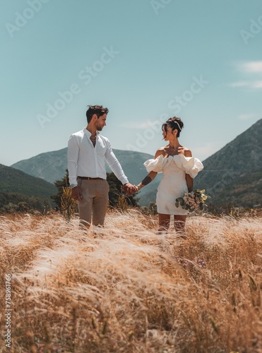 wedding photography, moment betxeen a bride and groom as they hold hands against a backdrop of majestic moutains and golden wheat fields © rdrgraphe