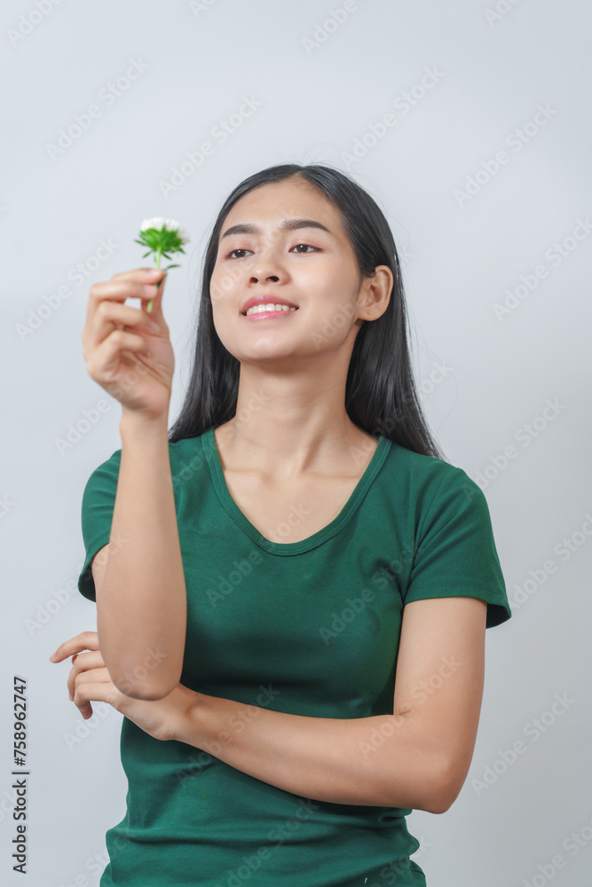 Beautiful young Asian woman in green t-shirt inhales the fragrance of white chrysanthemum flowers, isolated on white background. Beautiful young Asian woman in green t-shirt inhales the fragrance of white chrysanthemum flowers, isolated on white background.