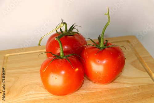 red round tomato on a wooden cutting board © Marie