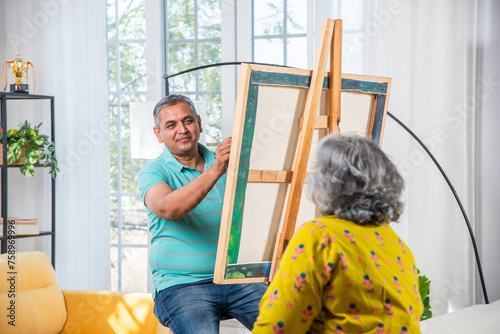 Senior Indian male artist painting picture in studio photo