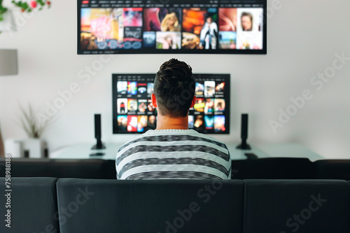 A person binge-watching a TV series on a streaming service.A man is lounging on the couch watching television in a Tshirt