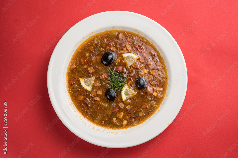 Soup with meat, tomato and olives on a red background Soup with meat, tomato and olives on a red background