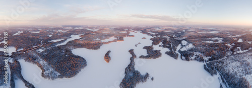 Winter in Finland; aerial view in panorama format over snow covered landscape with boreal forests and frozen lakes in southern Lapland at sunrise 