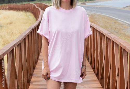 Young girl wearing blank oversized pink t shirt , pink t shirt mock up , pink tshirt for your rustic wooden  shirt design