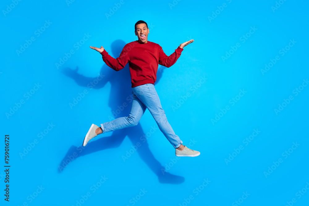 Full body profile portrait of cheerful energetic man jump run hands hold empty space isolated on blue color background
